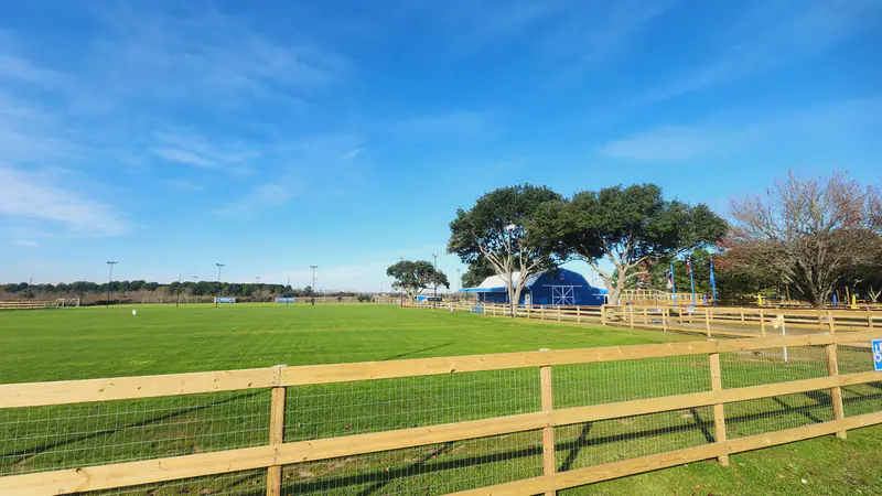 Fenced grass fields with the clubhouse in the distance