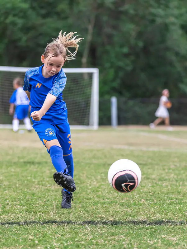 Player in blue striking the ball in front of goal