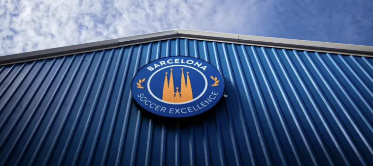 Barcelona Soccer Excellence crest on the blue clubhouse wall